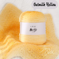 Ball of oatmilk yellow yarn with a label on a matching fabric background