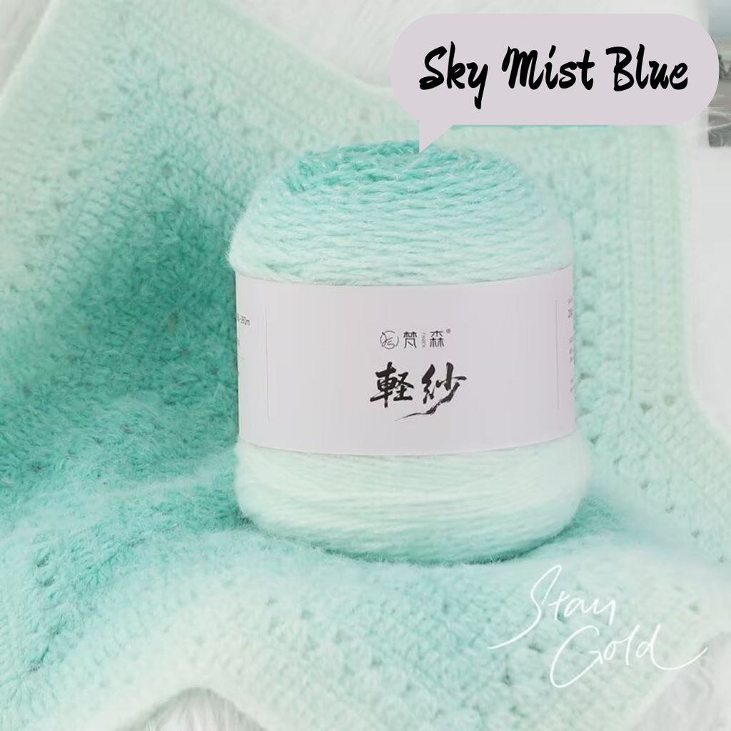 Ball of yarn labeled 'Sky Mist Blue' on a textured green background