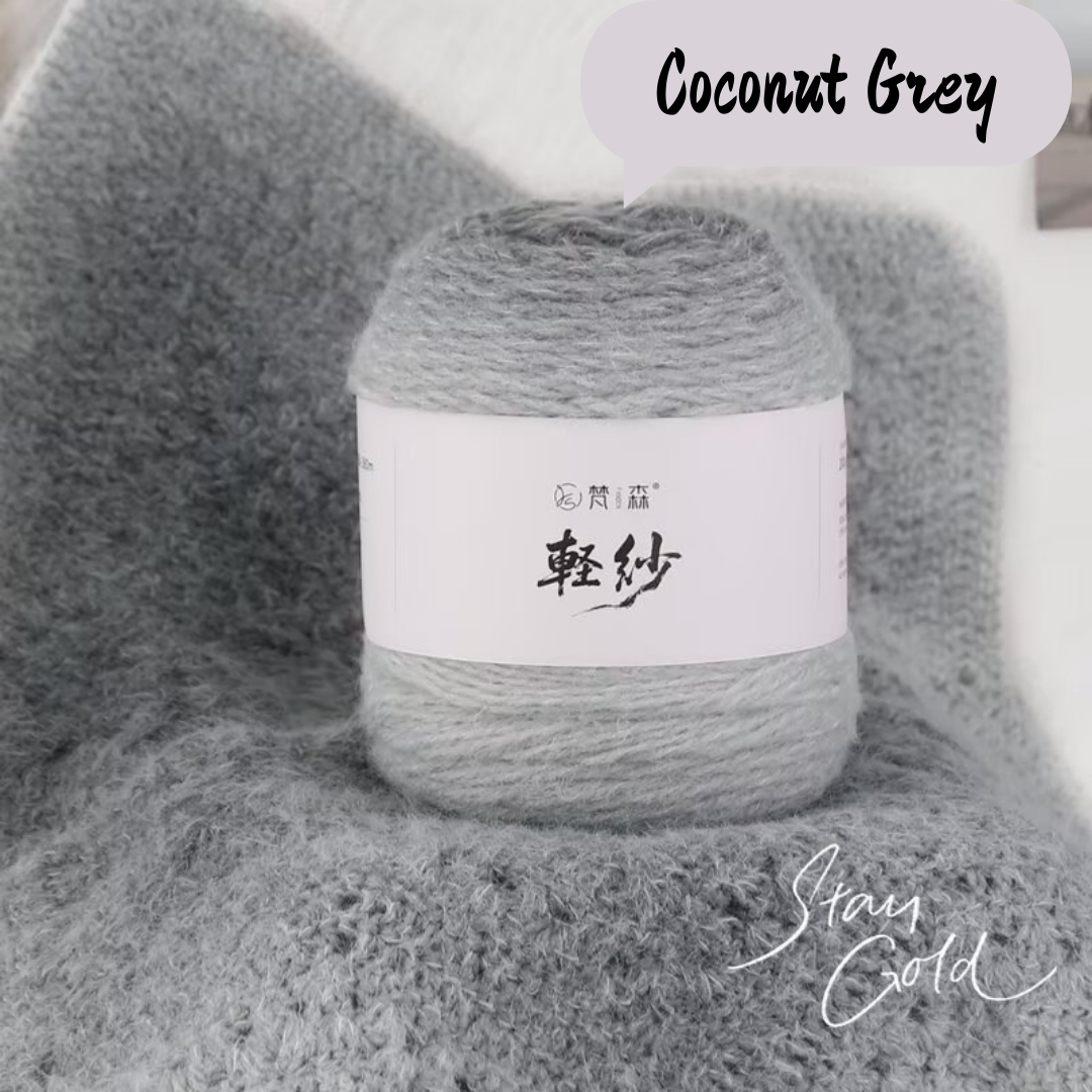 Ball of yarn labeled 'Coconut Grey' on a textured surface.