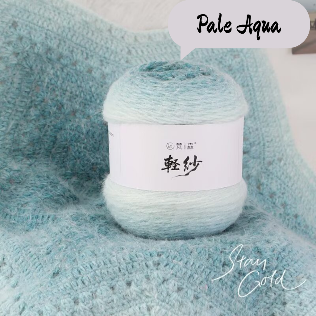 Ball of yarn labeled 'Pale Aqua' on a textured fabric background
