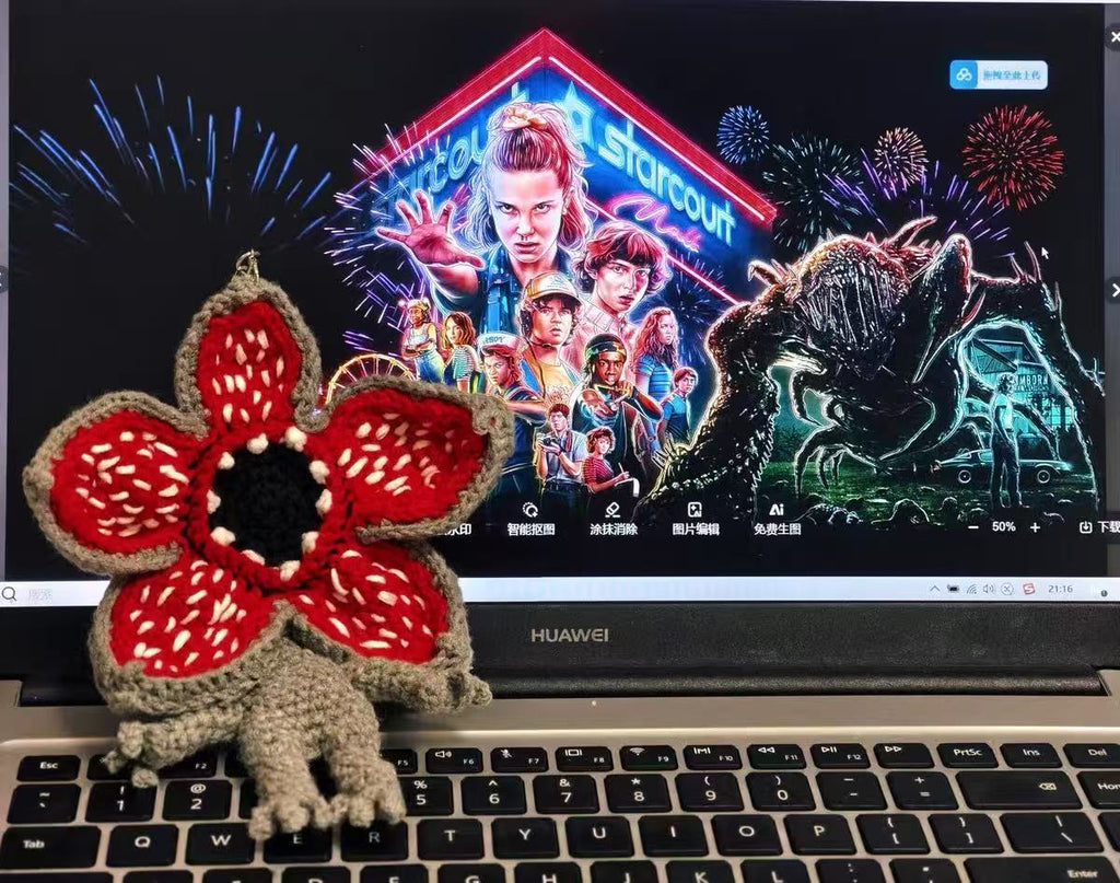 Laptop displaying a movie poster Stranger Thing with a Hand-crocheted Demogorgon plush toy
