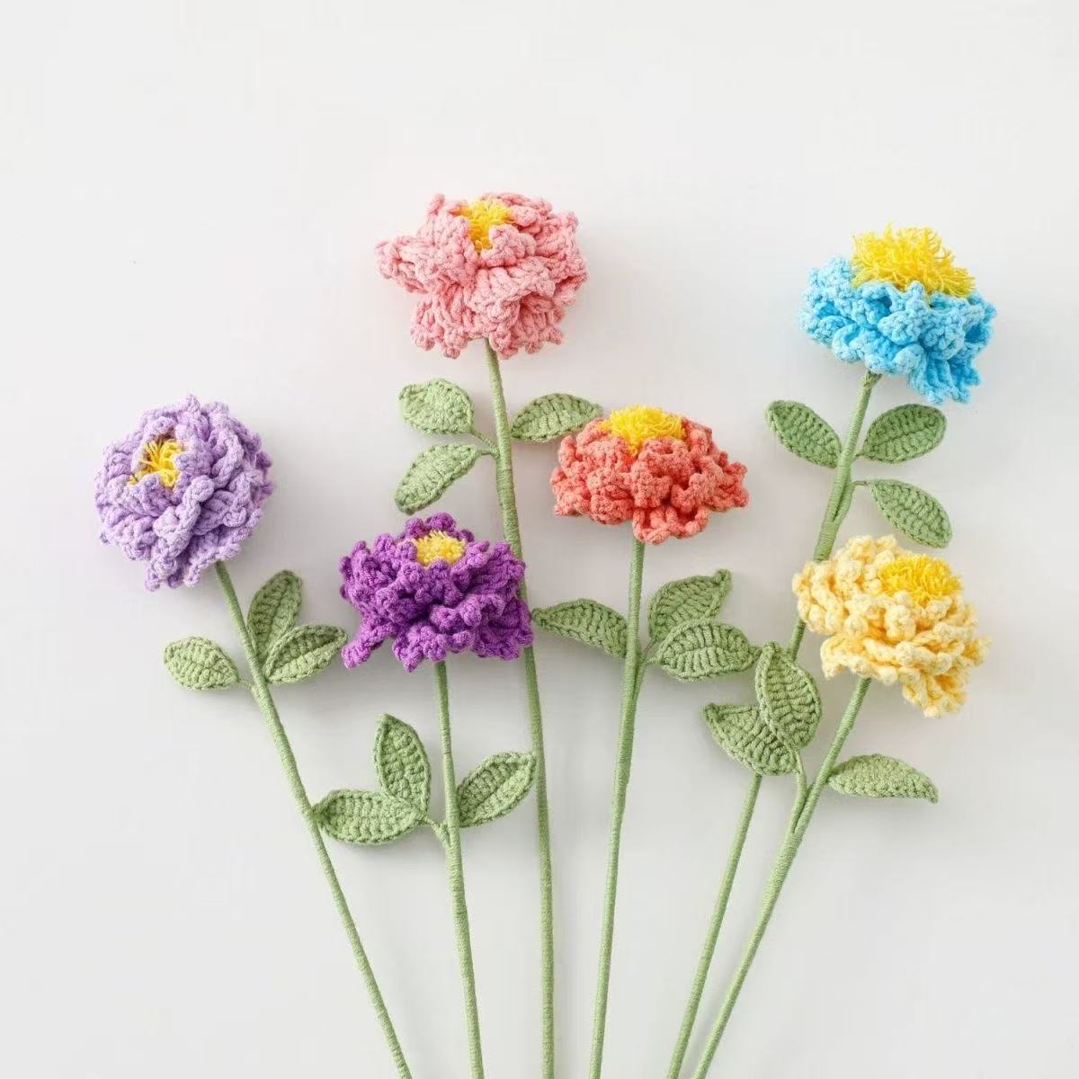 Colorful crocheted peony flowers on a white background