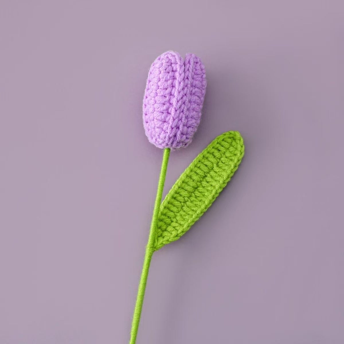 Handmade crochet tulip flower with purple knitted bud and green stem, decorative artificial crochet flower for home décor or gift