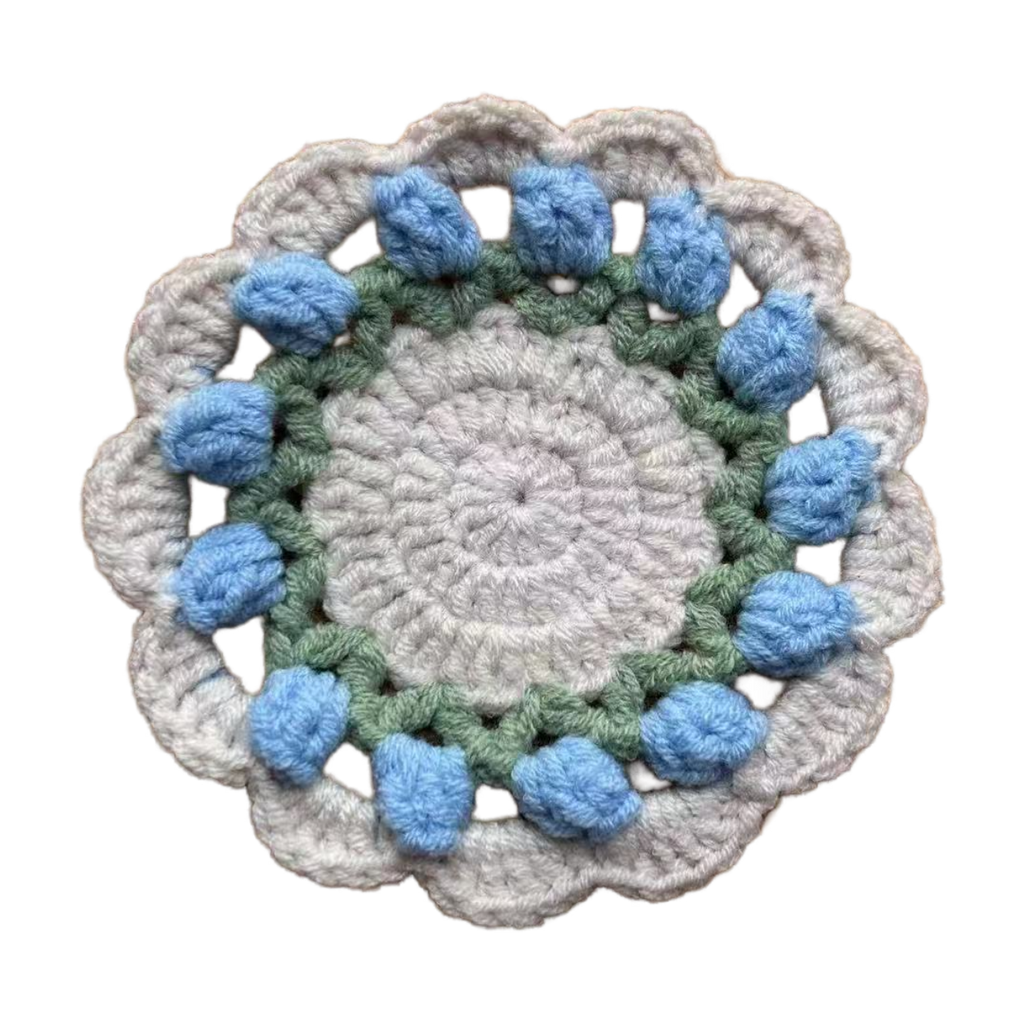 Crocheted coaster with blue and green accents on a white background