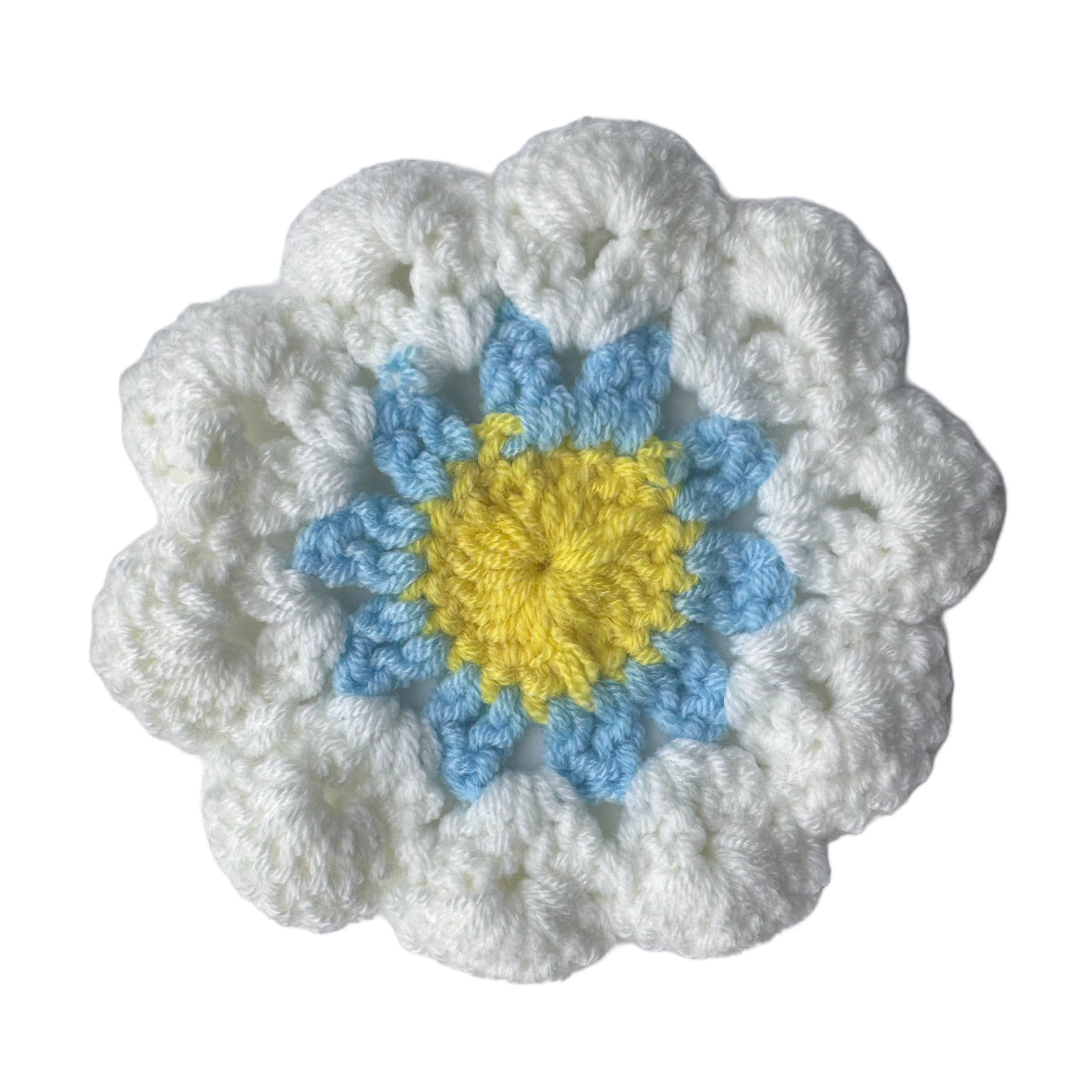 Crocheted flower with white outer petals, blue middle petals, and yellow center on a white background