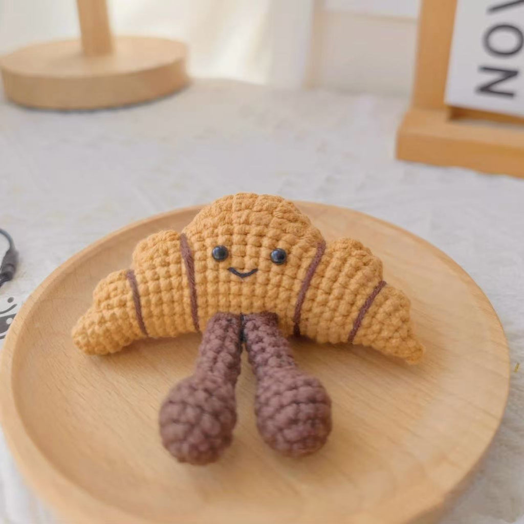 Handmade crochet croissant plush toy with smiling face, soft yarn bakery dessert ornament