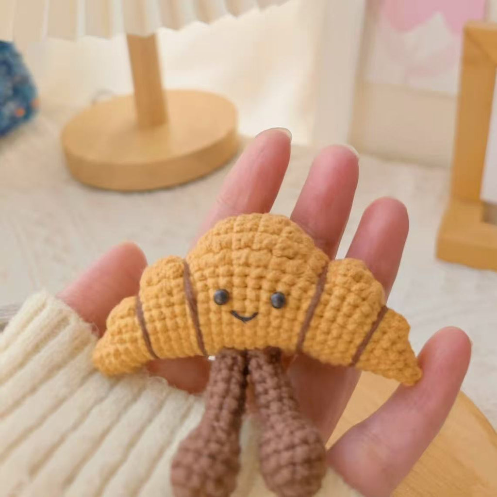 Handmade crochet croissant plush toy with smiling face, soft yarn bakery dessert ornament