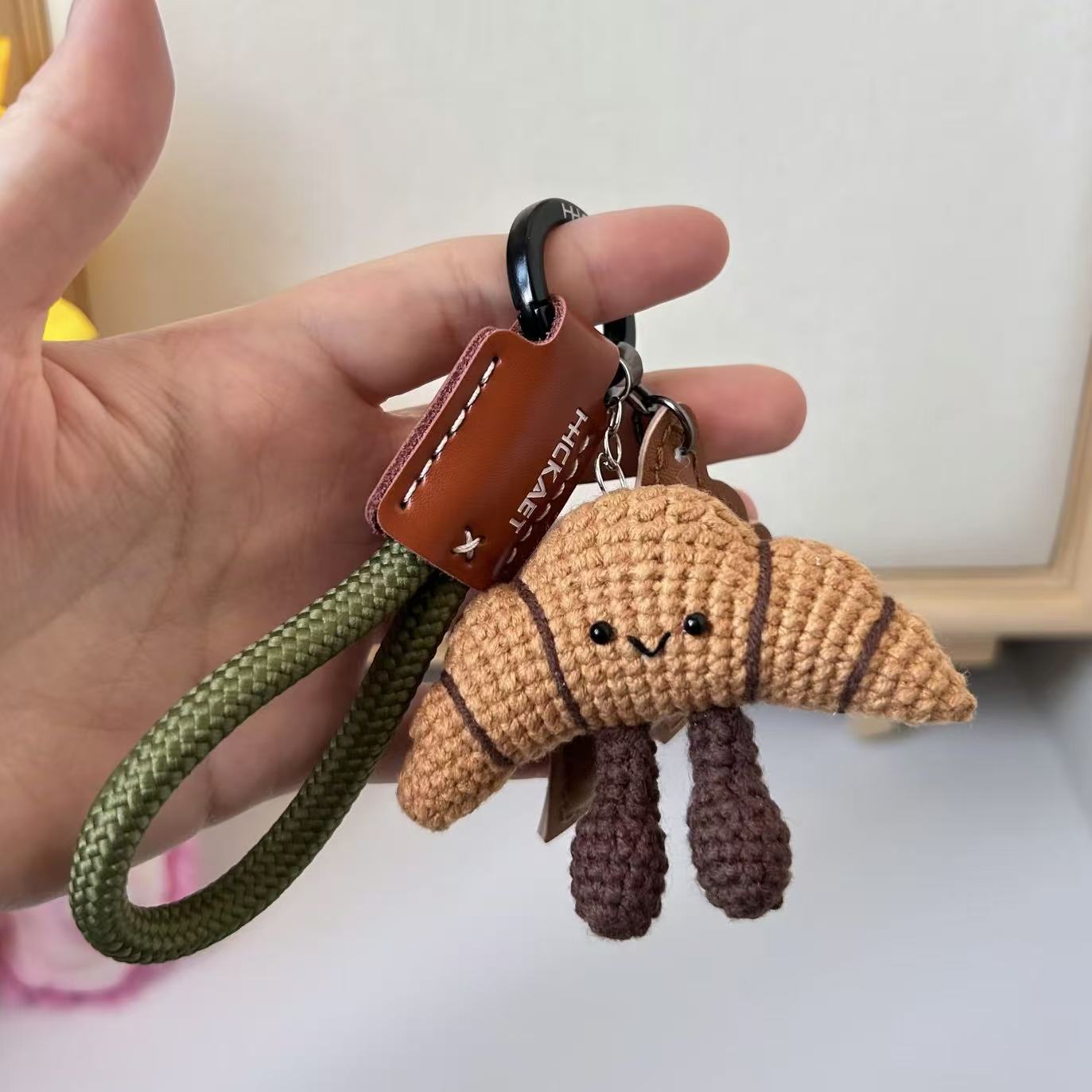 Handmade crochet croissant plush toy with smiling face, soft yarn bakery dessert ornament