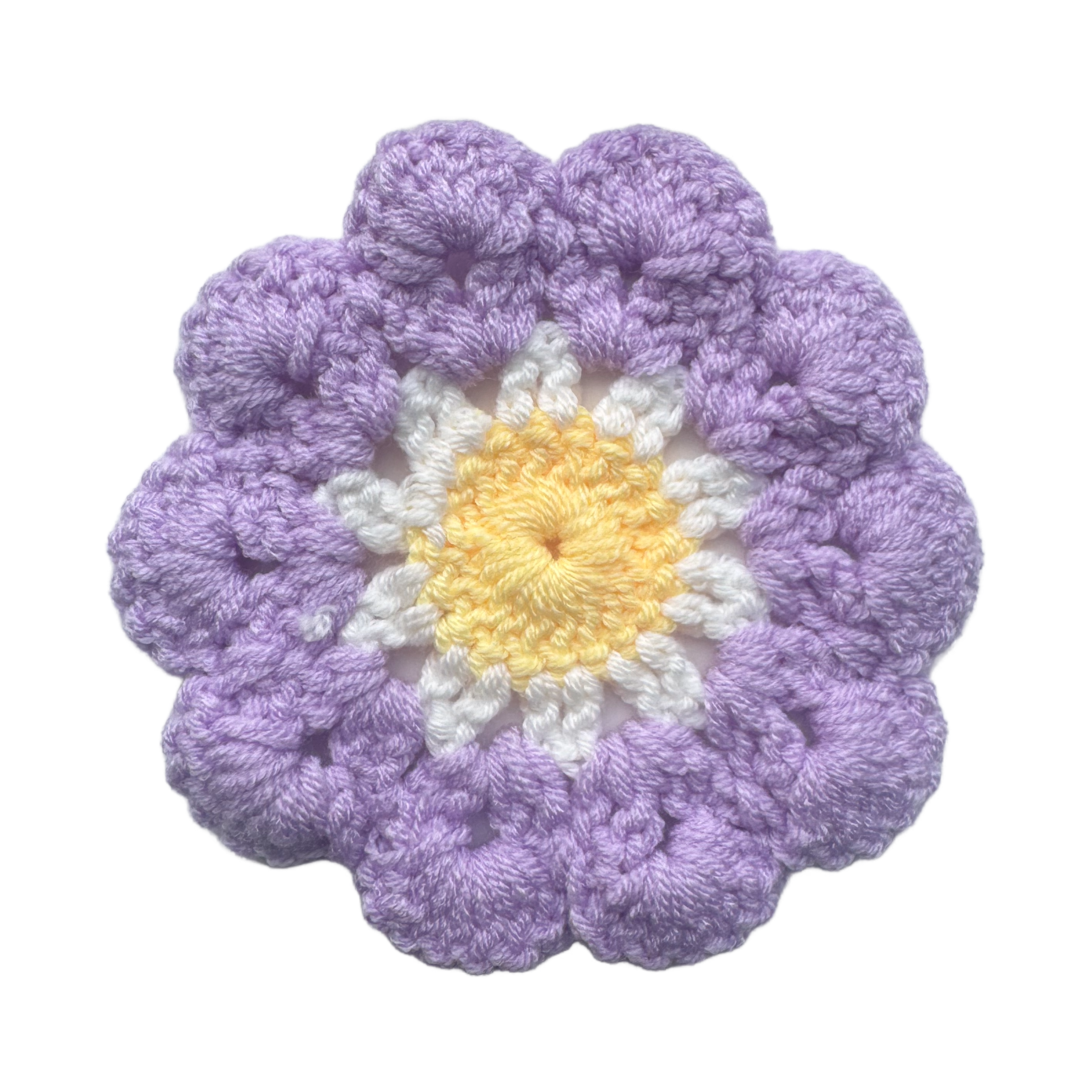 Crocheted flower with purple petals and a yellow center on a white background