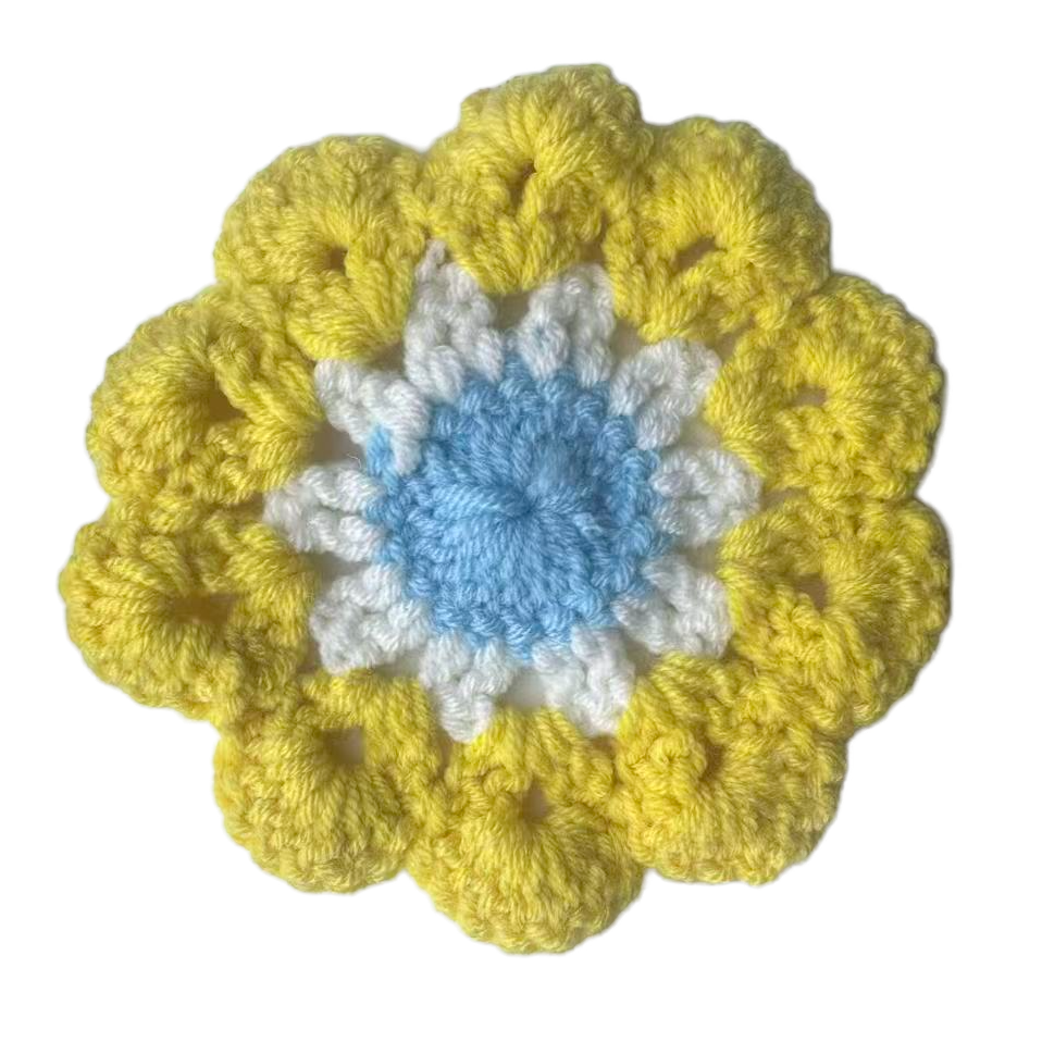 Crocheted flower with yellow petals and a blue center on a white background